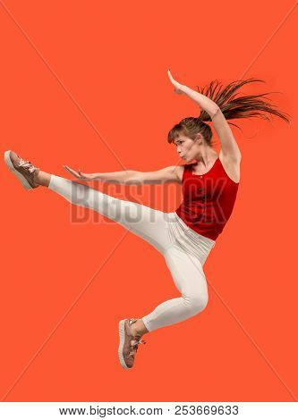 Freedom In Moving. Mid-air Shot Of Pretty Happy Young Woman Jumping And Gesturing Against Orange Stu