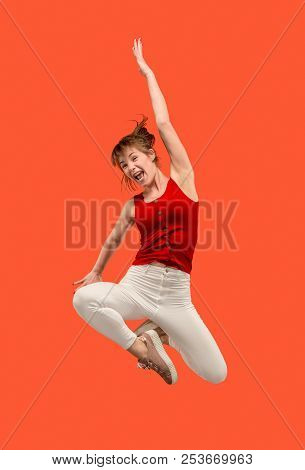 Freedom In Moving. Mid-air Shot Of Pretty Happy Young Woman Jumping And Gesturing Against Orange Stu