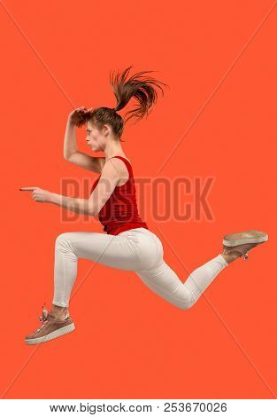 Freedom In Moving. Mid-air Shot Of Pretty Happy Young Woman Jumping And Gesturing Against Orange Stu