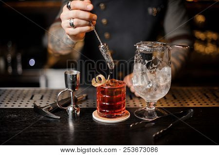 Barman Making A Fresh And Cool Orange Summer Cocktail Using Professional Bar Equipment On The Counte