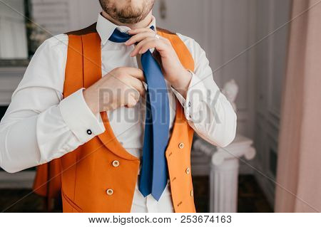 Cropped Indoor Image Of Bearded Young Unrecognizable Male Groom Dressed Formally, Ties Tie, Prepares
