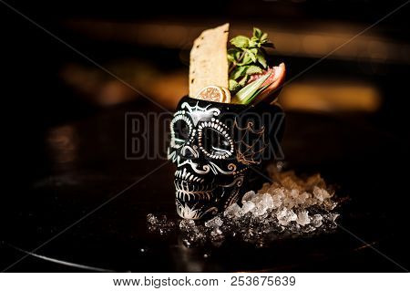 Black Scary Skull-shaped Glass Filled With Fresh And Sweet Summer Cocktail