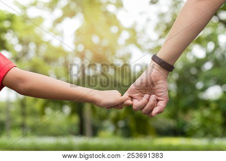 Mother And Son Hooking Up Finger Make Their Promise While Walking In The Park In Summer.