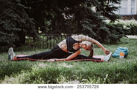 Young Sporty Woman Doing A Leg Split In Park. Toned Picture
