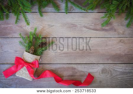 Christmas Firbranch With Cones, Red Polka Dot Ribbon In The Rustic Bag On Old Wooden Background With