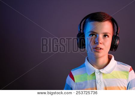Boy With Headphones Enjoys Music On Color Liht Background