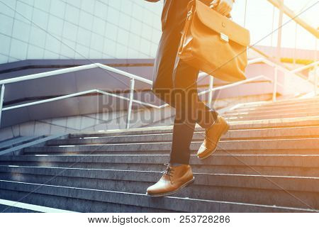 Guy Holding Leather Bag Walking Down Stairs. Businessman Wearing Suit And Brown Leather Shoes Walkin