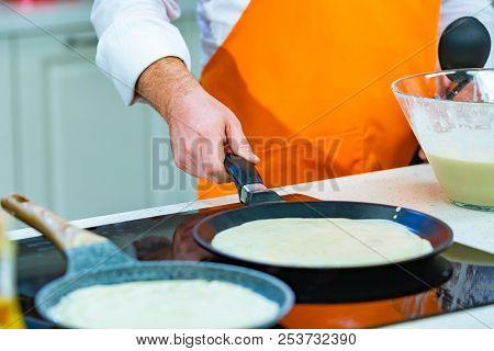 Kitchen Preparation: The Chef Fries Fresh Pancakes In Two Pans