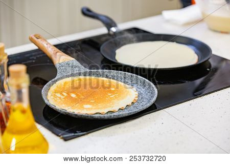 Kitchen Preparation: The Chef Fries Fresh Pancakes In Two Pans