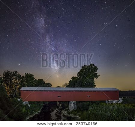 The Milky Way Adorns The Night Sky Over Houck Covered Bridge Crossing Big Walnut Creek In Rural Putn