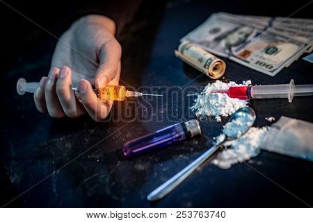 Male Junkie Hand Holding Drug Injection Syringe Near Heroin Powder, Spoon And Cigarette Lighter For 