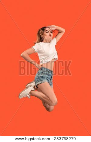 Freedom In Moving. Mid-air Shot Of Pretty Happy Young Woman Jumping And Gesturing Against Orange Stu