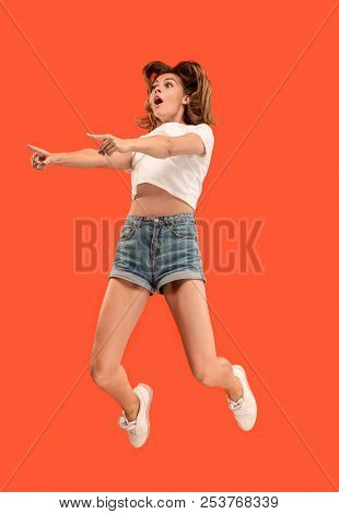 Freedom In Moving. Mid-air Shot Of Pretty Happy Young Woman Jumping And Pointing By Finger Against O