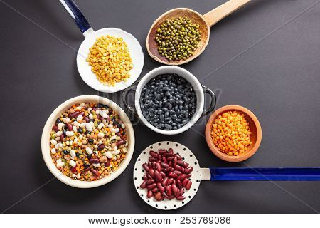 Top View Of Fflat Lay Of Assortment Of Legumes On Black Tabletop Background, In Scoop, Enameled Bowl