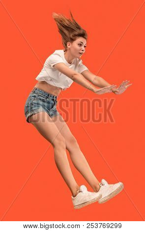 Freedom In Moving. Mid-air Shot Of Pretty Happy Young Woman Jumping And Gesturing Reject Against Ora