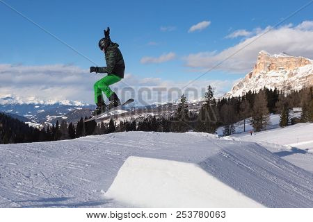 Snowboarder In Action: Jumping In The Mountain Snowpark.