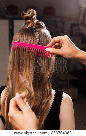 Model With A Topknot Having Her Hair Being Brushed By A Professional Hairdresser Using A Pink Brush 