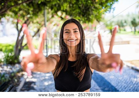 Happy Beautiful Girl Show Victory Sign And Smile. Urban Scene, City Life.