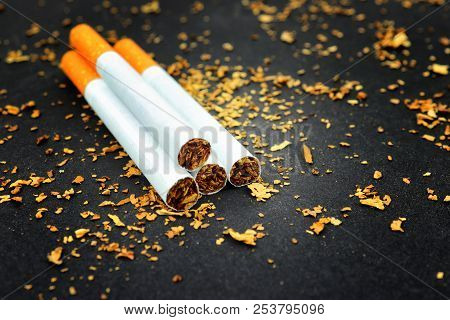 Cigarettes On A Black Background With Tobacco Around.four Cigarettes Sith Light Shine.