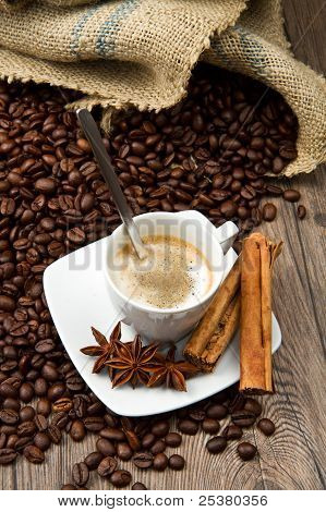 Xícara de café com saco de serapilheira de feijão assado na mesa rústica