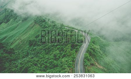 Aerial Top View Of Sky Road Over Top Of Mountain With Fog And Green Jungle After Raining In Morning