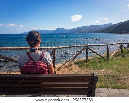 Woman With Backpack On A Bench Looking At Gulf Of Orosei South Of Cala Gonone On The Italian Island 