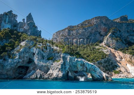 People Jumping Into The Water At Famous Cala Goloritze Beach On The Italian Island Of Sardinia