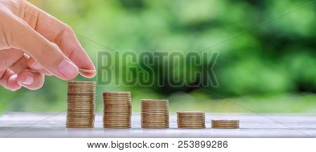Woman Hand Putting Coin, Gold Coins Stack On Wooden Table In The Morning Sunlight. Business, Investm