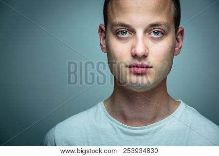 Portrait of a handsome young man, perfectly calm, facing the camera with emotionless expression