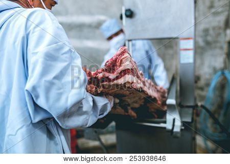 The Butcher Cutting Raw Meat Working With Friends In Slaughterhouse.