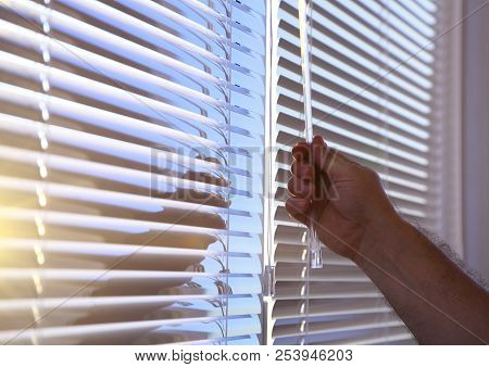 Man's Hand Closes The Horizontal Blinds On The Windows.