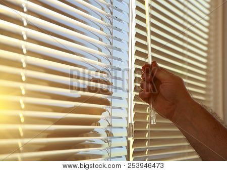 Man's Hand Closes The Evening Horizontal Blinds On The Windows.