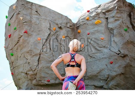 Photo from back of sportswoman climber with bag of soap against rock boulder
