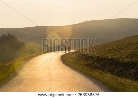 Cyclists In On The Road In Sunset. Two Man Cycling In Sunset In Countryside. Travel Cycling In Sunse