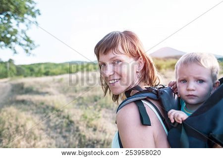 A Boy Is Sitting In A Backpack. The Kid Is Traveling With His Parents. Climbing With A Child. The Mo