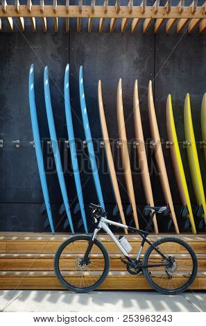 A bicycle in front of a group of surfboards for rent in a surf shop