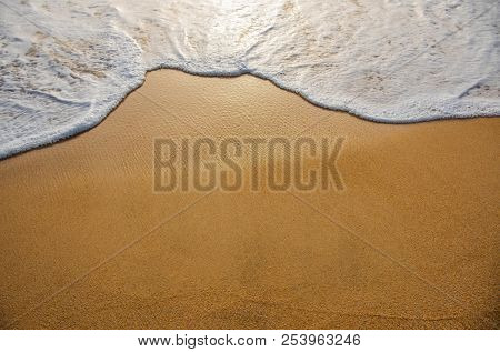 Golden sand with ocean water foam in the sea shore of a beach 