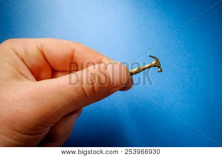 Hand Comically Holding Tiny Small Hammer In Macro Closeup