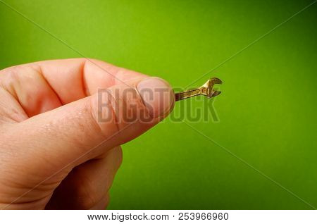 Hand Comically Holding Tiny Small Adjustable Wrench In Macro Closeup