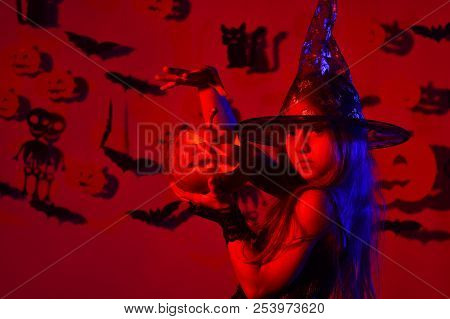 Kid In Witches Costume Holds Jack Lantern And Puts Spell.