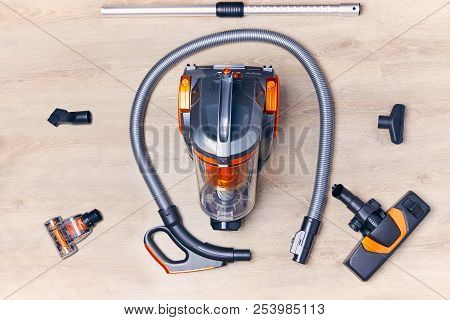 Top View Of A Modern Vacuum Cleaner With A Container With Nozzles And A Hose Spread Out Around It