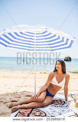 Young Beauty Latin Woman Lying On The Sand Under Sun Umbrella On The Sea Beach. Summer Vocation