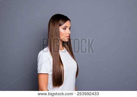 Confident Girl In A White T-shirt Is Standing In Half Turn And Looking Forward Isolated On A Gray Ba