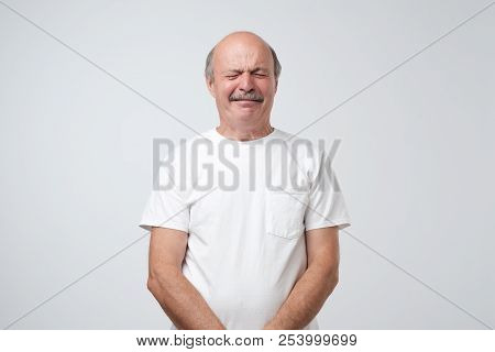 Unhappy Senior Man Like Weeper Crying Standing Over Gray Background. He Is Offended And Upset.
