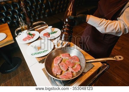 Chef Seasoning With Peppermill And Frying Tenderloin On A Pan