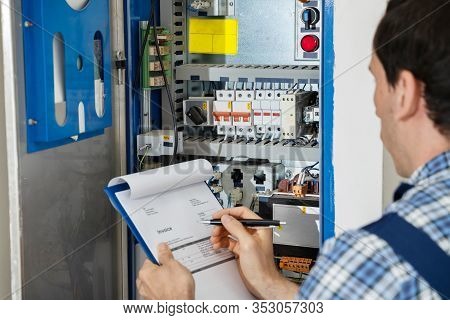 Cropped Image Of Male Electrician Holding Clipboard While Examining Fusebox