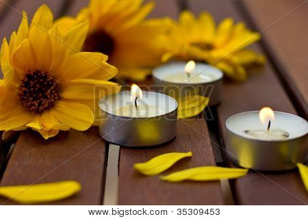 Dekorativa sammansättning med gula blommor och lite ljus