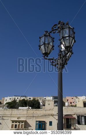 Stylish Wrought Iron Vintage Street Lamp With Blue Sky And Traditional Maltese Architecture