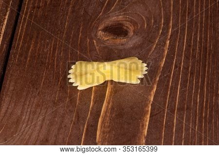 One Whole Yellow Pasta Farfalle On Brown Wood