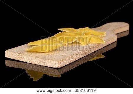 Lot Of Whole Yellow Pasta Farfalle On Wooden Cutting Board Isolated On Black Glass
